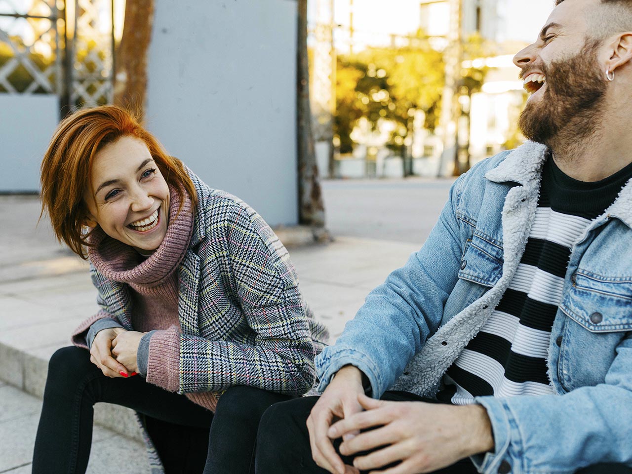Happy couple sitting outdoors laughing